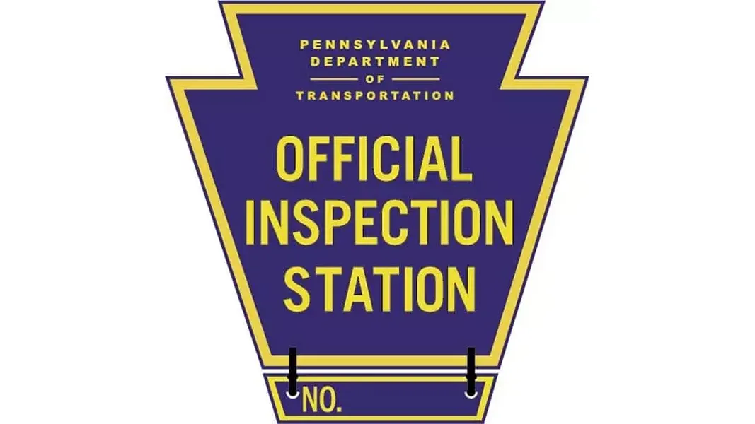 A blue and yellow keystone serving as an Official Inspection Station sign.